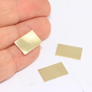 May include: Three rectangular pieces of brass sheet metal. The metal has a brushed finish and is a light gold colour.
