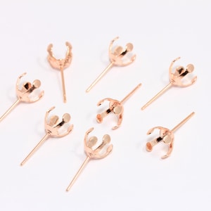 May include: Eight rose gold earring settings with prongs for attaching a stone or bead. The settings are on a white background.