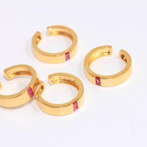 Peut inclure: Quatre boucles d'oreilles en or avec un accent de pierre rouge. Les boucles d'oreilles sont ouvertes et ont une finition lisse et polie.