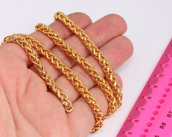 May include: Three gold chains of different lengths, laid out on a hand, with a pink ruler in the background.