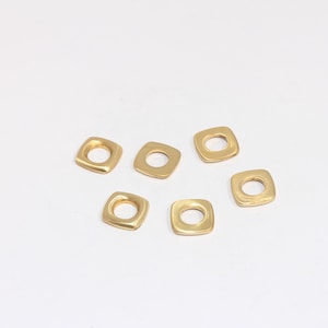 Puede incluir: Seis anillos de salto cuadrados de metal de color dorado con un agujero redondo en el centro.