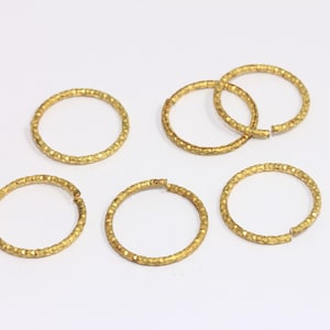 以下が含まれることがあります： テクスチャ加工された表面を持つ、金色の金属製のジャンプリングが6個あります。リングは開いており、ジュエリー作りに使用できます。