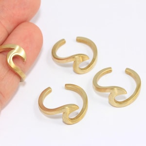May include: Four gold-coloured wave-shaped rings. The rings are open and can be adjusted to fit different finger sizes.