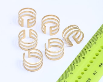 Puede incluir: Seis anillos de metal dorado con un diseño de triple banda. Los anillos están abiertos y tienen una forma ligeramente curvada.