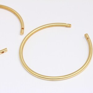 Peut inclure: Deux cerceaux en métal doré avec un petit espace de chaque côté. Les cerceaux sont ouverts et prêts à être utilisés pour la fabrication de bijoux.