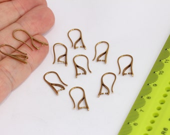 May include: Eight gold-toned earring hooks with a loop at the top and a small opening at the bottom. The hooks are arranged in a scattered pattern on a white surface.