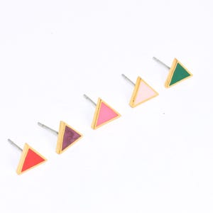 May include: Five pairs of triangle-shaped earrings with gold frames and different colored enamel inserts. The colors are pink, green, red, purple, and light pink.