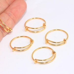 Könnte beinhalten: Vier verstellbare goldfarbene Ringe mit einem Doppelband-Design. Die Ringe sind aus Metall und haben eine glatte Oberfläche.
