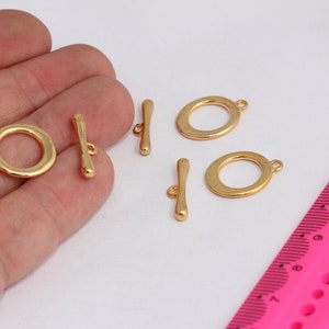 May include: Gold-toned metal toggle clasps with round rings. The clasps are approximately 2.5 cm in length.
