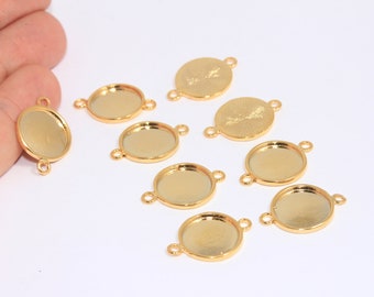 May include: Gold-coloured metal bezel trays with loops for jewellery making. The trays are in various shapes, including oval and round, and are designed to hold small items or embellishments. The trays are shown on a white surface.