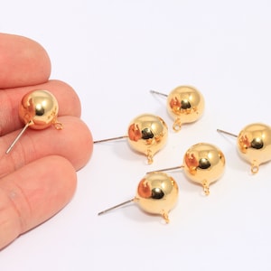 Pode incluir: Seis achados de brincos de metal dourado com forma de bola redonda e um laço na parte inferior. Os achados têm um pino reto na parte superior.