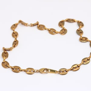 May include: A gold chain necklace with oval-shaped links. The chain is made of metal and has a lobster claw clasp.