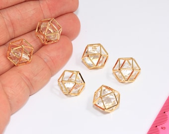 Puede incluir: Seis colgantes geométricos dorados con inserciones transparentes en forma de cristal. Los colgantes están dispuestos sobre una superficie blanca. Los colgantes tienen un diseño en forma de jaula. Probablemente para la fabricación de joyas.
