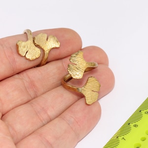 Puede incluir: Dos anillos de color dorado con un diseño de hoja de ginkgo. Los anillos son ajustables y se pueden usar en cualquier dedo.