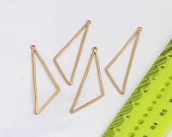 May include: Four gold-colored metal triangle pendant charms with a small loop at the top. The charms are arranged on a white surface with a green ruler in the background.