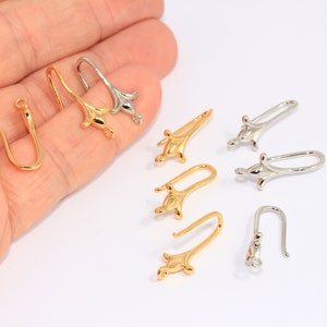 May include: A close-up of a variety of gold and silver earring hooks. The hooks are made of metal and have a delicate, floral design. They are perfect for adding a touch of elegance to any jewelry project.