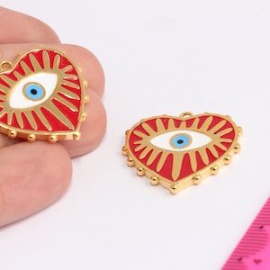 May include: Two gold-tone heart-shaped charms with red enamel and a white evil eye design. The evil eye has a blue pupil.