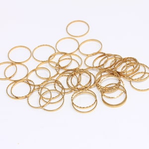 Puede incluir: Un montón de anillos de metal de color dorado, todos del mismo tamaño y forma, con una superficie texturizada.