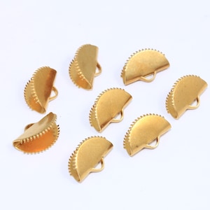 May include: Eight gold-coloured metal half-circle clasps with a scalloped edge and a small loop at the top.
