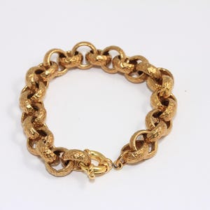 May include: A gold chain bracelet with a textured finish. The bracelet has a clasp closure.