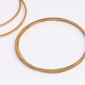 May include: Three gold-coloured metal rings of varying sizes. The rings are stacked on top of each other.