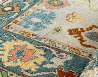 May include: A rolled up rug with a blue, beige, and orange floral pattern. The rug has a detailed border with a repeating pattern.