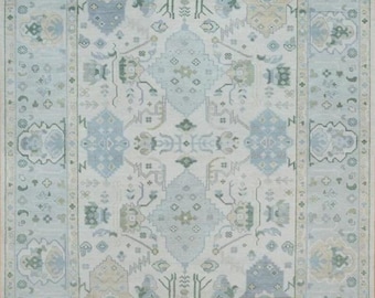 May include: A light blue rug with a traditional Persian design. The rug has a white background with intricate patterns in shades of blue, green, and beige. The rug has a fringed border.