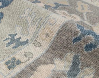May include: Close-up of a light blue, gray, and white patterned rug. The rug has a subtle, woven texture.