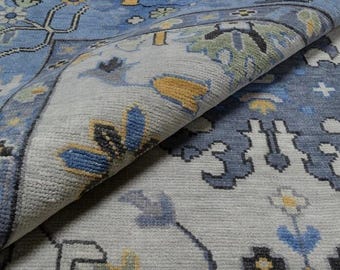 May include: A close-up of a blue and white patterned rug with a floral design. The rug is folded in half, showing the intricate details of the woven pattern.