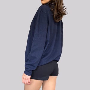 K&ouml;nnte beinhalten: Ein marineblaues Langarmshirt mit Kragen und schwarze Shorts. Das Shirt besteht aus einem weichen Material. Das Model tr&auml;gt das Shirt und die Shorts.