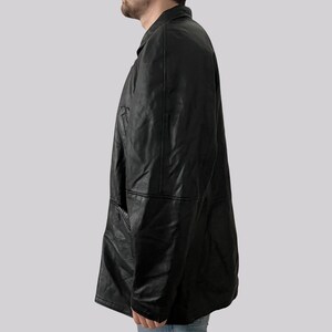 May include: A black leather jacket with a collared neckline and a button-down front. The jacket has a classic design with a tailored fit and a pocket on the chest. The jacket is made of a smooth, shiny leather material.