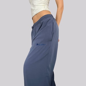 Könnte beinhalten: Blaue Sporthose mit Kordelzugbund und Seitentaschen. Die Hose hat eine lockere Passform und ein kleines gesticktes Logo am linken Bein. Der Stoff scheint leicht zu sein und eignet sich für Freizeit oder Workouts.