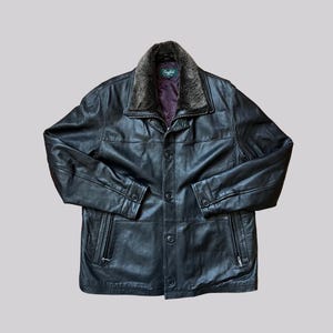 May include: Black leather jacket with a faux fur collar. The jacket has a button-up front, two side pockets with zippers, and buttoned cuffs. The collar has a dark brown and gray color. The jacket is a classic style.