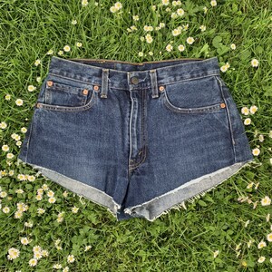 May include: Dark blue denim shorts with a frayed hem. The shorts have a high waist and are made of a thick, durable fabric.