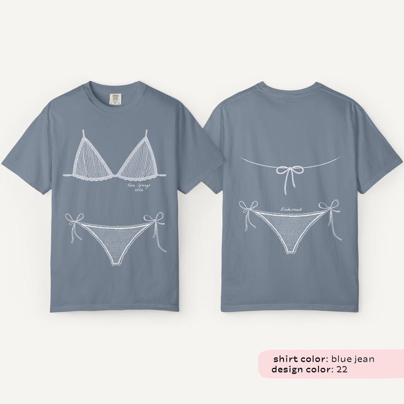 May include: Blue jean colored t-shirts with white line drawings of a bikini top and bottom on the front and back. The front of the shirt has the text "Palm Springs 2023". The back of the shirt has the text "Bikini".