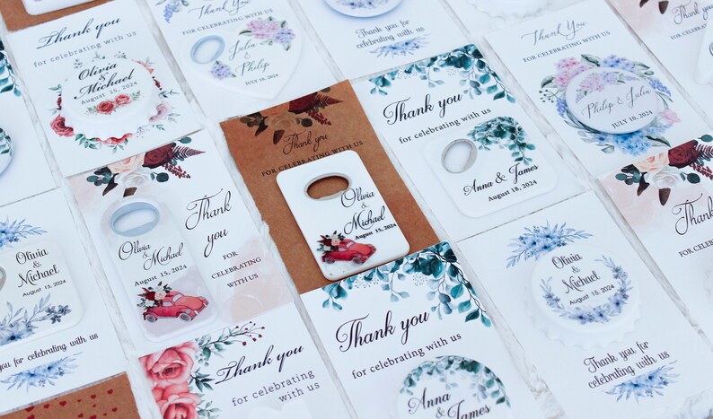 May include: Assortment of wedding favor tags with floral designs and bottle opener favors. The tags feature the names of the couples and their wedding dates. The bottle openers are white with a red car and floral designs.