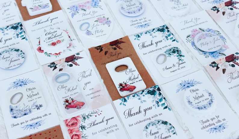 Pode incluir: Conjunto de abridores de garrafas para lembrancinhas de casamento com v&aacute;rios desenhos florais e os nomes dos casais. Os abridores de garrafas s&atilde;o de metal e t&ecirc;m um fundo branco com uma mensagem de agradecimento.