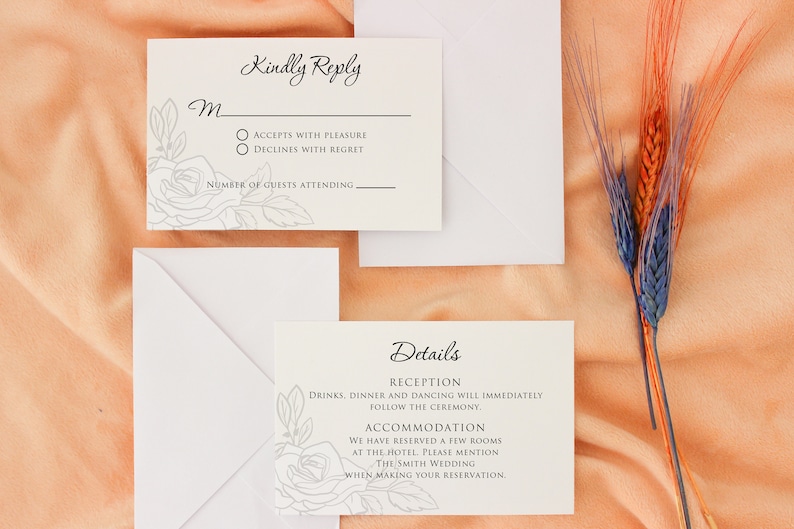 May include: Wedding invitation suite with RSVP and details cards, and white envelopes. The cards are off-white with floral line art and elegant script. The RSVP card includes options to accept or decline. Dried wheat stalks in orange and blue are in the background.
