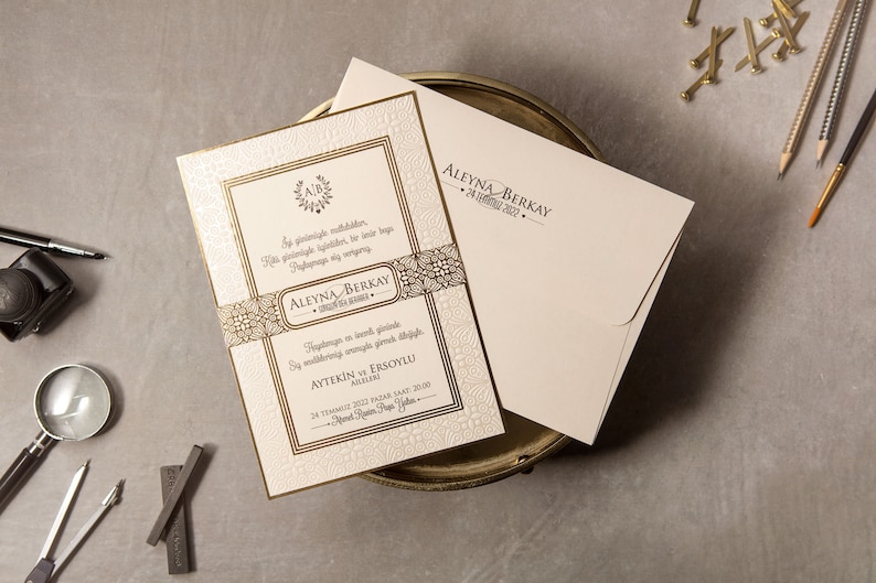 May include: A white wedding invitation with gold accents and intricate designs. The invitation features the names "Aleyna & Berkay" and the date "24 July 2022".