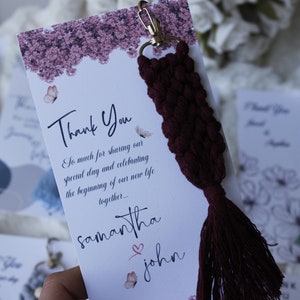 May include: A white card with the text "Thank You" and the names "Samantha" and "John" with a heart symbol. The card is attached to a maroon tassel keychain.