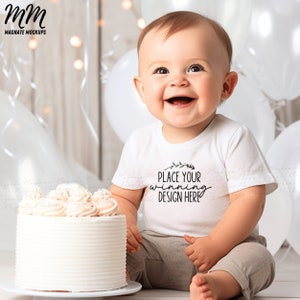 May include: A white baby onesie with the text "Place your winning design here" and a small floral design. A baby is wearing the onesie and sitting in front of a white cake with white frosting.