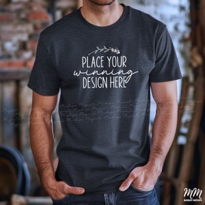 May include: A dark gray t-shirt mockup with the text "Place your winning design here" on the front. The shirt is being worn by a person with their hands in their pockets.