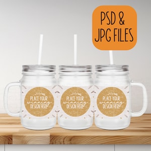 Può includere: Tre barattoli di vetro trasparente con coperchi e manici argentati. Ogni barattolo ha un adesivo rotondo marrone con il testo "PLACE YOUR WINNING DESIGN HERE".