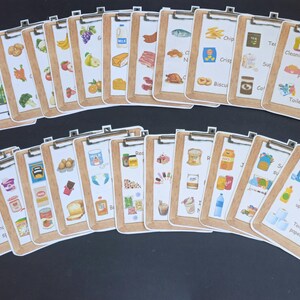Puede incluir: Un conjunto de 20 tarjetas de lista de verificaci&oacute;n coloridas con im&aacute;genes de varios art&iacute;culos de comestibles y productos para el hogar. Las tarjetas est&aacute;n etiquetadas con los nombres de los art&iacute;culos, como "Leche", "Patatas fritas", "Productos de limpieza" y "Art&iacute;culos de tocador".