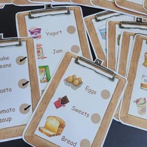 Puede incluir: Un conjunto de tarjetas de memoria coloridas con im&aacute;genes de varios alimentos, incluyendo huevos, pan, yogur, mermelada y dulces. Cada tarjeta tiene una lista de verificaci&oacute;n con un c&iacute;rculo al lado del nombre del alimento.