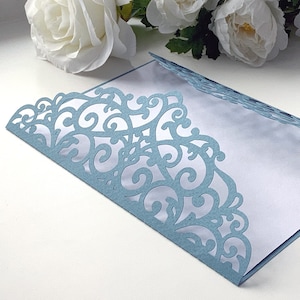 May include: A light blue envelope with a delicate, intricate lace design cut out around the edges. The envelope is open and the inside is white.