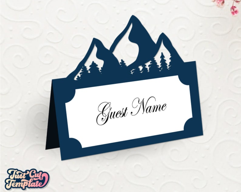 May include: A blue mountain-shaped place card with a white rectangle for writing a guest name. The text "Guest Name" is written in cursive on the card.