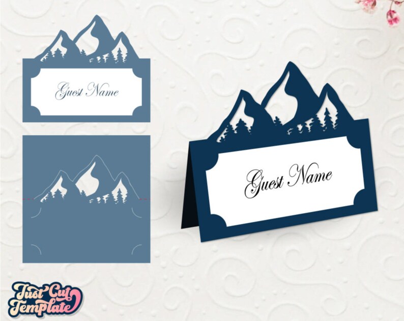 May include: A blue mountain range silhouette with trees, used as a place card holder. The card is white with the text "Guest Name" in black.