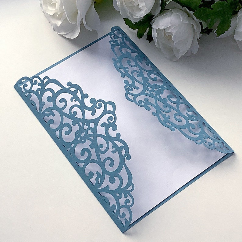 May include: A light blue laser-cut envelope featuring a delicate, intricate floral design. The envelope is folded and ready for use for a special occasion.