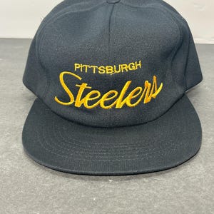 May include: Black baseball cap with a gold embroidered Pittsburgh Steelers logo.